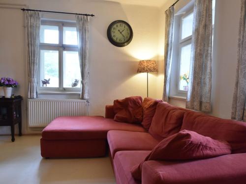 a living room with a couch and a clock on the wall at Chata Hnyk in Zlatá Olešnice