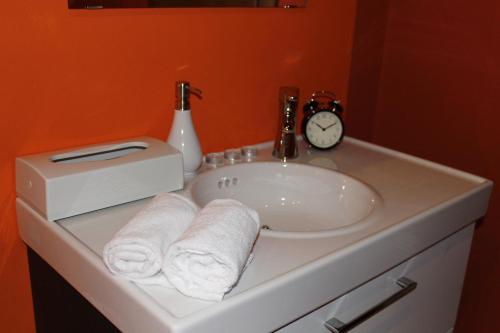 a bathroom sink with towels and a clock on it at Hotel Baita Clementi in Bormio