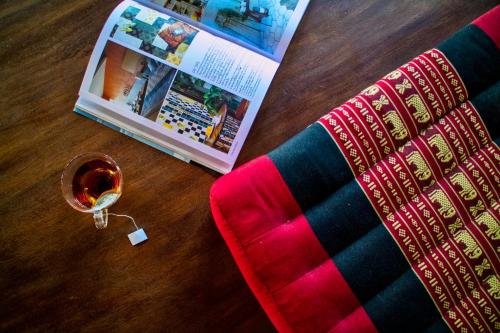 a book and a glass of wine on a table at Cozycomo Chiang Dao - Wiang Mek in Chiang Dao