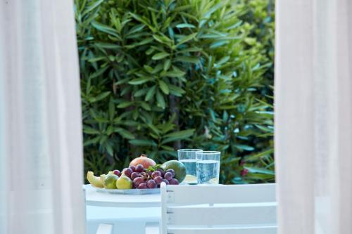 a plate of fruit on a table with glasses of water at Mr and Mrs White Paros in Naousa