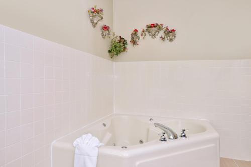 a white bathroom with a sink and flowers on the wall at Regency Inn Geneseo IL I-80 in Geneseo