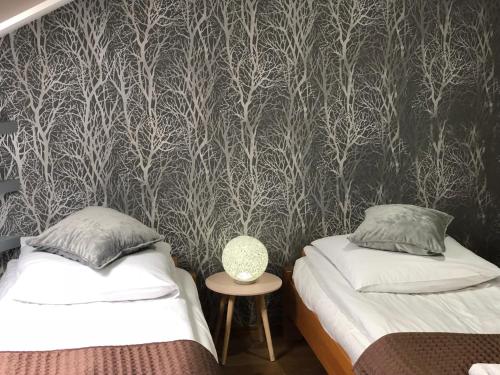 a bedroom with two beds and a wallpaper with trees at Sokół in Racibórz