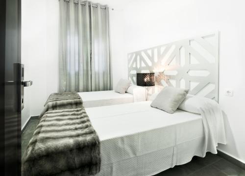 a white bedroom with two beds and a blanket at Narayana Casa Camilo in El Cerro de Andévalo