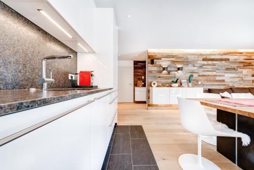 - une cuisine avec des placards blancs et un comptoir avec un évier dans l'établissement Appartement Zimba Blick by A-Appartments, à Bürserberg