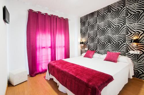 1 dormitorio con 1 cama blanca grande y cortinas rosas en Narayana Casa Camilo, en El Cerro de Andévalo