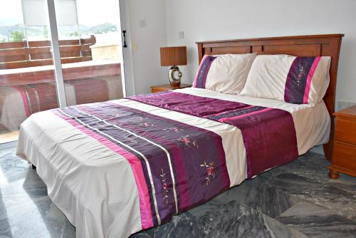 een slaapkamer met een bed met een paarse en witte deken bij Argaka 1 Bedroom Apartment - Private Heated Jacuzzi - Large Communal Pool in Argaka