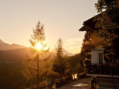 a house with the sun setting in the mountains at Apartmenthaus Vergissmeinnicht in Abtenau