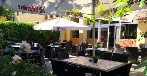 um restaurante ao ar livre com mesas e cadeiras e um guarda-sol em Hotel zum Schwan em Nachterstedt
