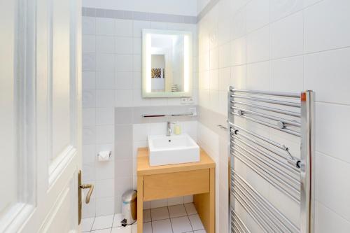 a white bathroom with a sink and a mirror at Dušní Apartments in Prague