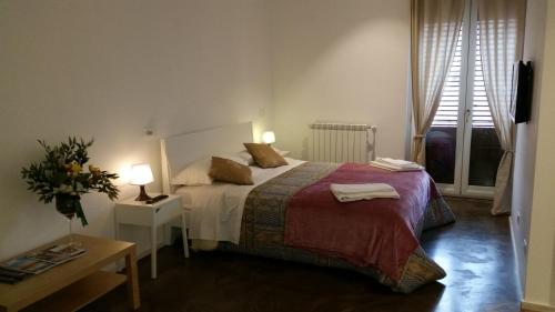 Un dormitorio con una cama y una mesa y dos ventanas. en Palermo Rooms, en Palermo