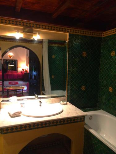 La salle de bains est pourvue d'un lavabo, d'une baignoire et d'un miroir. dans l'établissement Riad A La Belle Etoile, à Sale