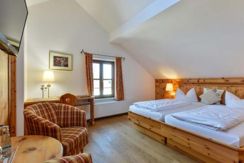 um quarto de hotel com uma cama e uma cadeira em Landgasthof zum Erdinger Weissbräu em Rosenheim