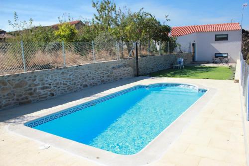 a swimming pool in a yard with a stone wall at Curral D Avó Turismo Rural & SPA in Caçarelhos