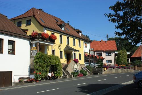 Hotel Gasthof zum Biber في Motten: منزل اصفر وزهور على جانب شارع