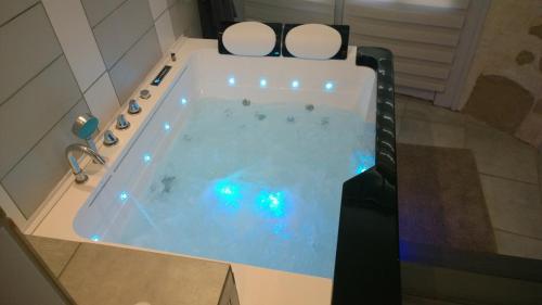 een groot bad met verlichting in de badkamer bij La Miellerie in Saint-Antoine
