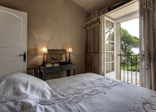 a bedroom with a bed and a window and a table at Maison de charme Pampelonne Saint Tropez in Saint-Tropez