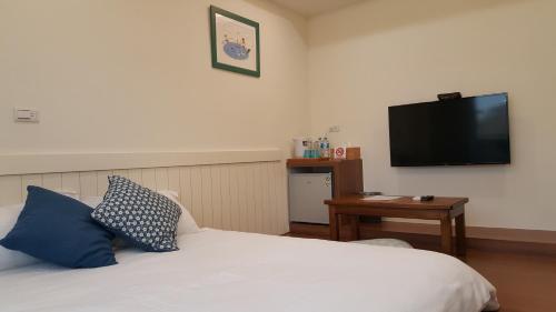 a bedroom with a bed and a flat screen tv at Summer Tree Homestay in Tainan