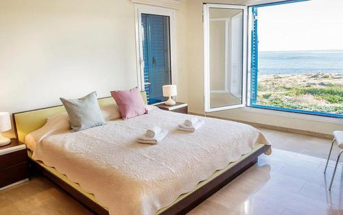 a bedroom with a bed with a view of the ocean at Luxury Bay View Villa 20 Right On Τhe Beach in Protaras