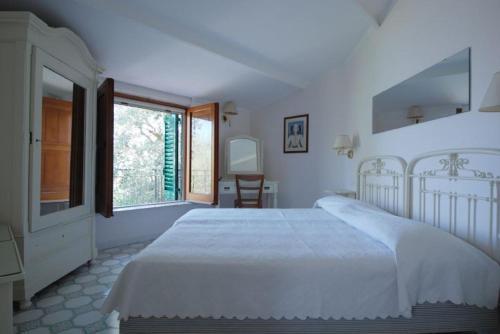 een witte slaapkamer met een groot bed en een raam bij LA FENICE -white house- homeinsorrento- in Massa Lubrense