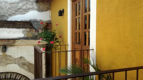 a yellow building with a door and a balcony with flowers at Hotel Candelaria Antigua in Antigua Guatemala