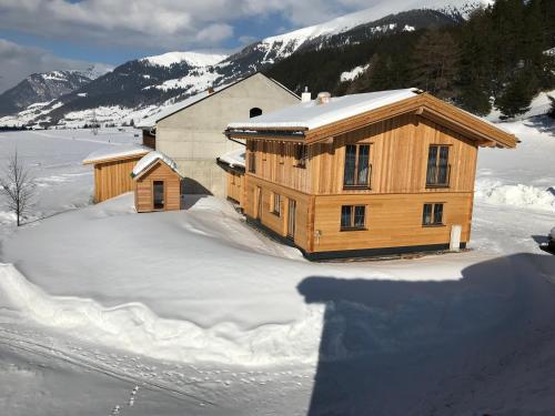 a wooden house in the snow with mountains in the background at Chalet Fuhrmannslochhof in Nauders