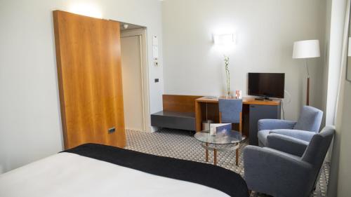 a hotel room with a bed and two chairs and a television at Gran Hotel Albacete in Albacete
