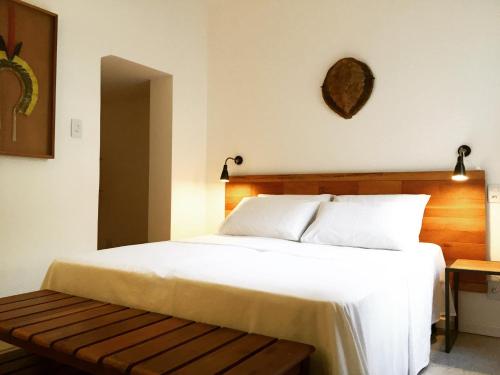 1 dormitorio con cama blanca grande y banco en Viver Bahia Pousada, en Salvador