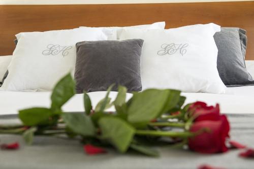 a bed with two pillows and a red flower on it at Gran Hotel Albacete in Albacete