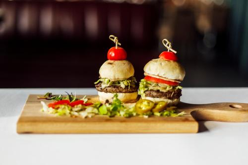 two sandwiches sitting on a cutting board with vegetables at Novotel Montréal Aéroport in Dorval