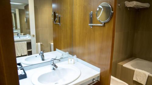 a bathroom with two sinks and a mirror and a tub at Gran Hotel Albacete in Albacete
