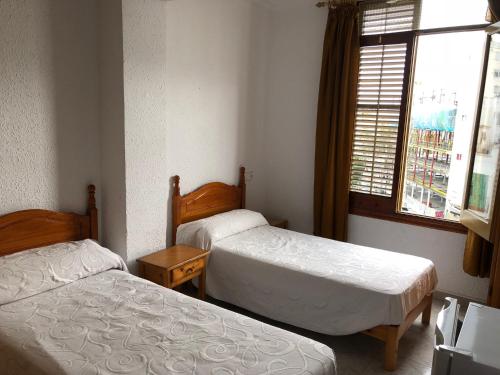two beds in a small room with a window at Casa de Huespedes el Almendro in Ibiza Town