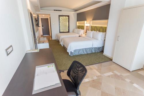 Habitación de hotel con 2 camas y escritorio con ordenador portátil. en Holiday Inn Queretaro Zona Diamante, an IHG Hotel en Querétaro