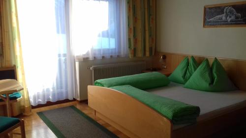 een slaapkamer met een bed met groene kussens erop bij Pension Anderlehof in Sankt Lorenzen im Lesachtal