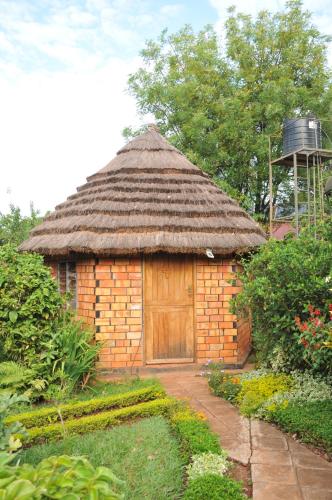 a small brick building with a thatch roof at New Court View Hotel in Masindi