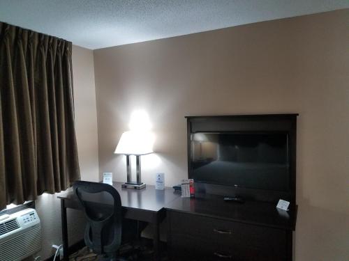 a hotel room with a desk with a television and a lamp at Americas Best Value Inn and Suites Bismarck in Bismarck