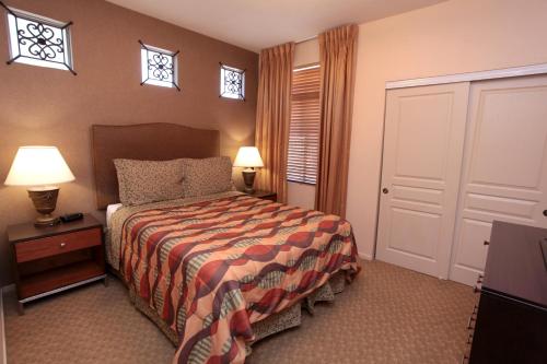 a bedroom with a bed and two lamps and windows at The Cliffs at Peace Canyon in Las Vegas