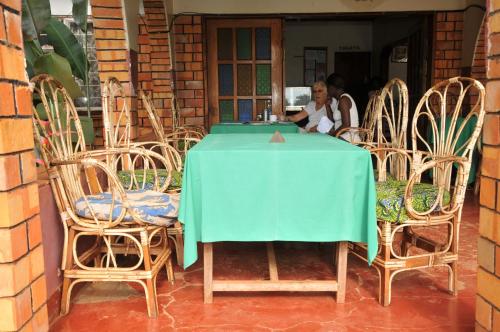 Masindi的住宿－New Court View Hotel，坐在桌子上,带两把椅子的女人