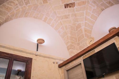 a room with a stone ceiling and a tv at Apulia '800 in San Pietro Vernotico