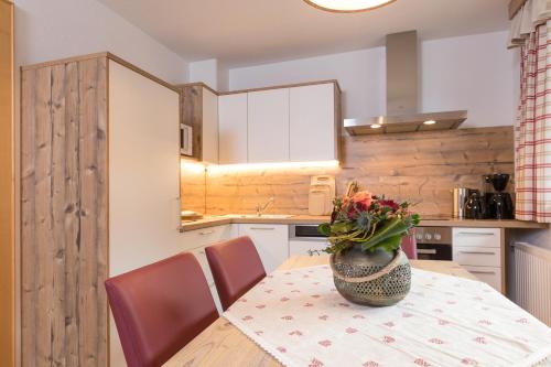 a kitchen with a table with a vase of flowers on it at Pension Margretenhof in Fulpmes