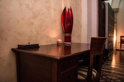 a desk with a red vase and a candle on it at Apulia '800 in San Pietro Vernotico