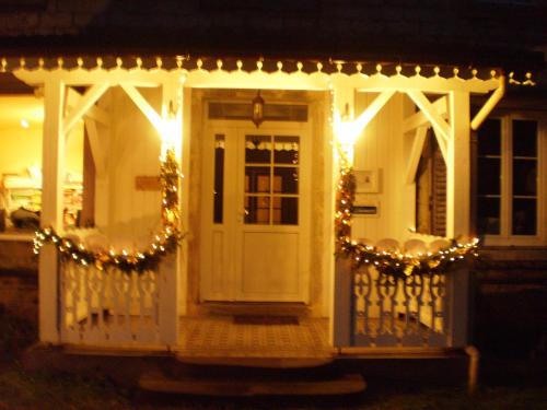 a house with a porch with christmas lights at Chambres d'Hôtes le Clos des Lesses in Fresse-sur-Moselle