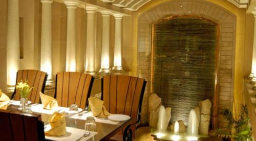 a dining room with tables and chairs and a fireplace at The Imperial Palace in Rajkot