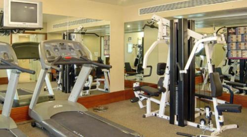 a gym with several tread machines and a television at The Imperial Palace in Rajkot