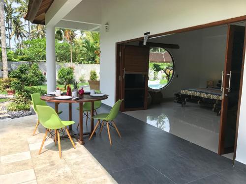 a dining room with a table and green chairs at Villa Rizki Candidasa in Candidasa