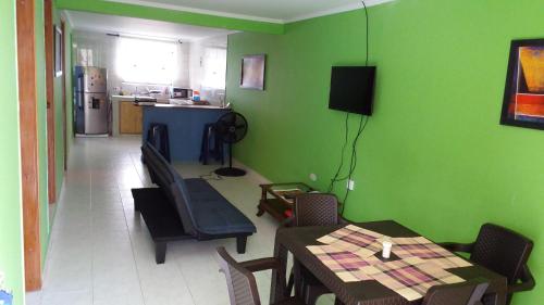 uma sala de jantar com paredes verdes e uma mesa e cadeiras em Miss Leila em San Andrés