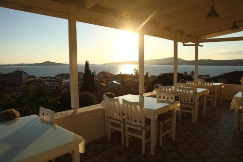 a row of tables and chairs on a terrace with the sunset at Cesmeli Han in Ayvalık