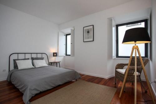 a bedroom with a bed and a lamp and a chair at Place Of Moments Urban-Suites in Ponta Delgada