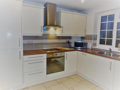 a white kitchen with white cabinets and a sink at Faraday Place in Nottingham