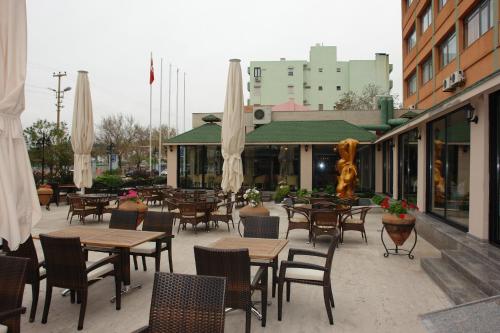an outdoor patio with tables and chairs and umbrellas at Buyuk Truva Hotel in Canakkale