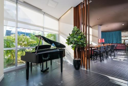 a piano in a room with a table and chairs at Novotel Montréal Aéroport in Dorval